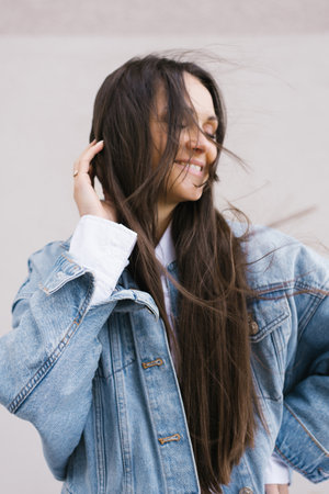 Young woman with long hair is wearing a blue jacket and smiling. She is happy and confidentの写真素材