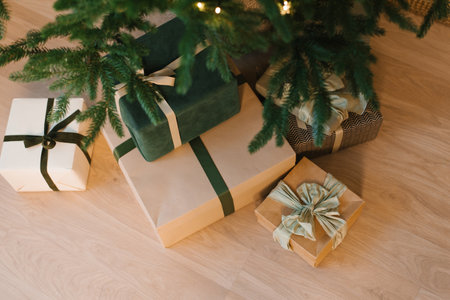 Stack of presents are on a wooden floor, with a green box in the middle