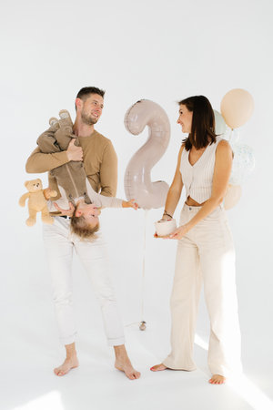 Happy family with their celebrate sons his two year anniversary with a cake and balloonsの写真素材