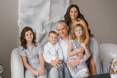Happy family of five is posing for photo in front of couch at home