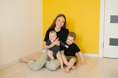 Young happy woman sits on the floor with her two children. Scene is happy and lovingの写真素材