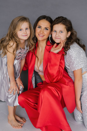 Young woman is posing with two young daughter girls in red jacket. Scene is happy and friendlyの写真素材