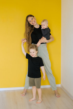 Young mother is holding her two young sons. Woman is smiling and the children are happyの写真素材