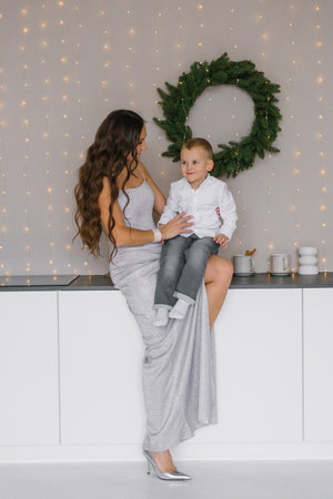 Happy mother and son are sitting on kitchen counter. Scene is warm and cozyの写真素材
