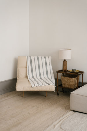 White armchair with a striped blanket, lamp on table clean and simple living roomの写真素材