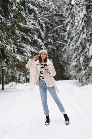 Happy woman holding candy cane in her hand and smiling at winter parkの写真素材