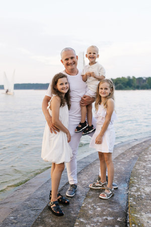 Father and three children are posing for photo on beach. Scene is happy and family-orientedの写真素材