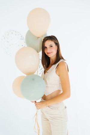 Young caucasian woman is holding a bunch of birthday balloons in her handの写真素材