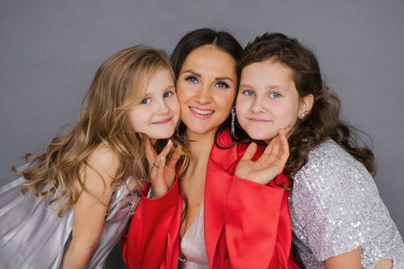 Young happy mother is posing with two young daughters in red jacket. Scene is happy and friendlyの写真素材