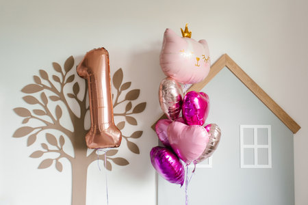 Festive arrangement of pink, gold, and cat shaped balloons next to a large metallic number one, perfect for a first birthday celebration.の写真素材