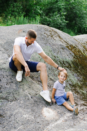 Father and son spending quality time together outdoors in a green summer nature setting, showing bonding and joy.の写真素材