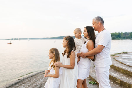 Happy family of five is standing on a pier overlooking the waterの写真素材