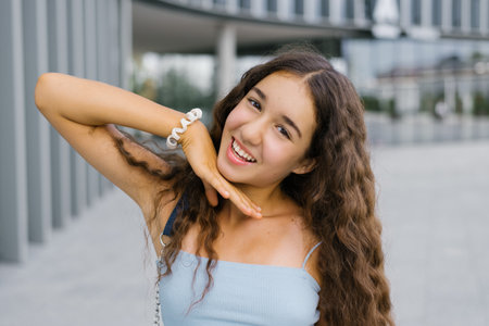 A stylish girl from Generation Alpha posing confidently in a modern urban setting wearing a casual denim outfit.の写真素材