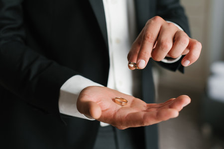 The groom displays gold wedding rings in his hand, symbolizing love, unity, and the beginning of a lifetime together.の写真素材