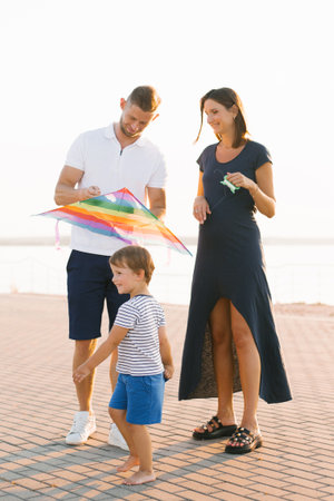 A cheerful family preparing to fly a colorful kite on a sunny day near the waterfront, showingcasing joy and togetherness.の写真素材
