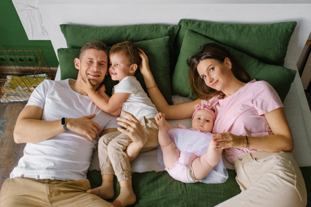 Parents with son and daughter laughing together in a bright modern home interior, capturing...