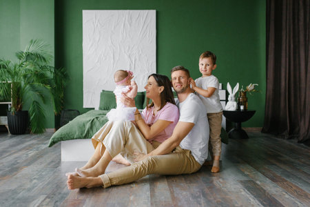 Parents with their son and baby daughter sitting closely together, sharing a warm family moment in a...