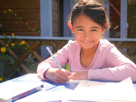 Little girl doing her homework in the garden during coronavirus containmentの写真素材