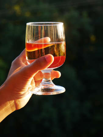 Close-up of a glass of wine held by the hand of a black woman with a black backgroundの写真素材