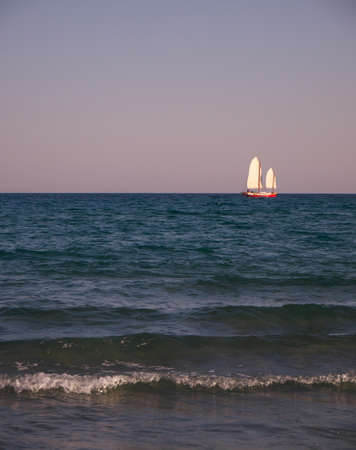 Photograph of a sailboat sailing off the seaの写真素材