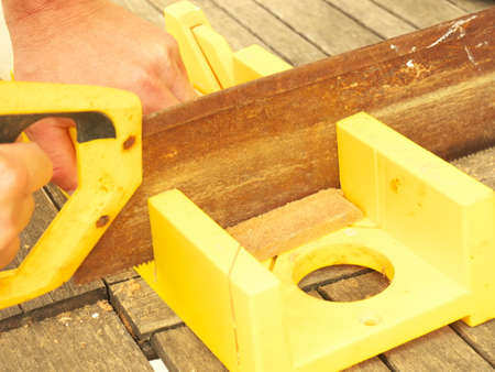 Close up on the hands of a man cutting timber with a sawの写真素材