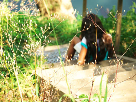 Photo with background metis girl seen from behind reading a book on a staircase outside at the waters edgeの写真素材