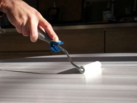 Close-up on the hand of a man doing DIY, painting a piece of furniture with a brush