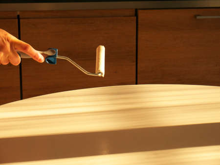 Close-up on the hand of a man doing DIY, painting a piece of furniture with a brush