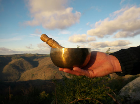 Singing bowl held in a man's hand with background sky and natureの写真素材