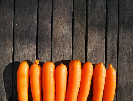 A top view of delicious carrots in a line on the wooden surfaceの写真素材