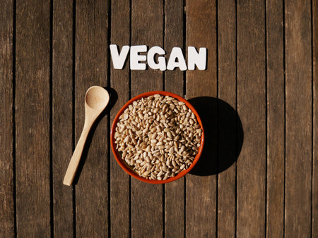 Top view of a bowl with sunflower seeds with text veganの写真素材