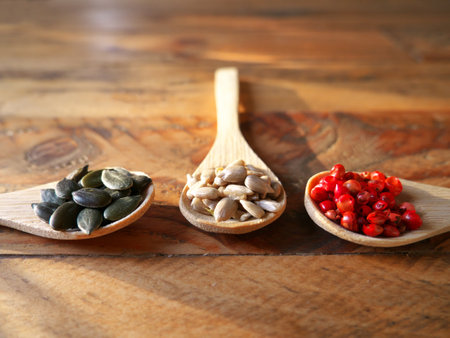 Three wooden spoons filled with rice, pink pepper, pumpkin seeds and lentils. View from aboveの写真素材