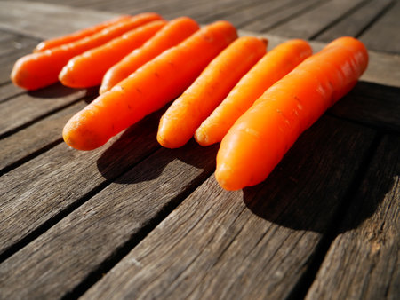 A selective focus shot of delicious carrots in a line on the wooden surfaceの写真素材
