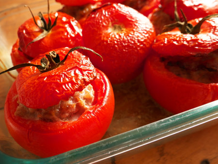 A high angle shot of baked tomatoes stuffed with tuna on glasswareの写真素材
