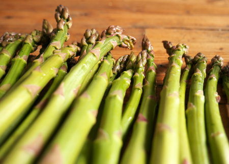A closeup of ripe asparagus on a wooden table in the kitchenの写真素材