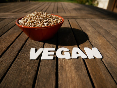 A closeup shot of abowl with sunflower seeds with a text ''Vegan''の写真素材