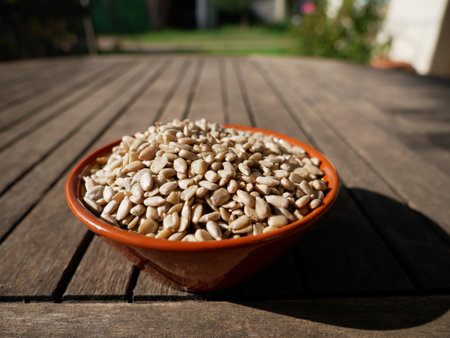 A close-up of sunflower seeds in a bowl on a wooden tableの写真素材