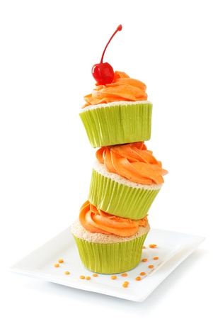 Stacked vanilla cupcakes with orange colored vanilla frosting               の写真素材