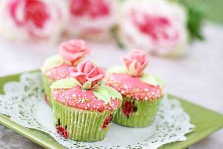 Vanilla cupcakes with pink frosting decorated with pearls and roses made of fondant                  の写真素材