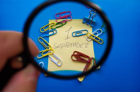 September 1st Day Concept. September 1, calendar with magnifier on a blue background and paper clips.の写真素材
