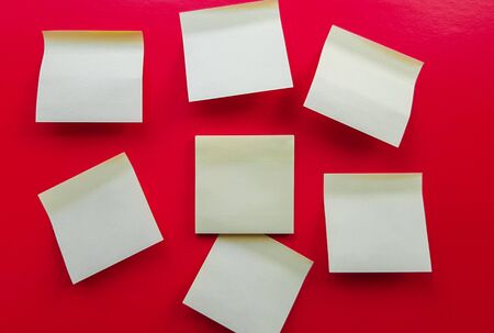 Blank yellow sticky notes on a red background, business work concept. Yellow commemorative stickers on the red wall. Layout.の写真素材