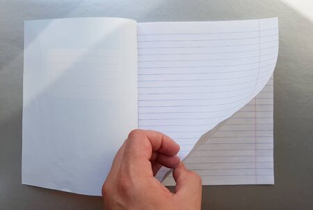 Design concept - Top view of a high quality male hand leafing through a sheet of blue striped notebook. Top view, copy space, flat lay.の写真素材