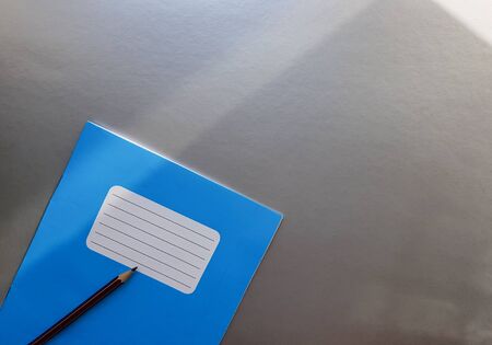 New blue notebook with pencil on a gray table with sun rays from the window backgroundの写真素材
