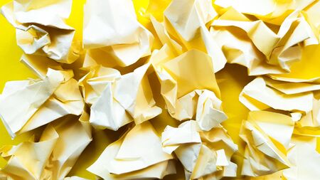 Ball crumpled paper ball isolated on a yellow background. Crumpled paper for texture. Crumpled paper after a brainstorming was thrown into the bin. A piece of yellow crumpled paper on a yellow background.の写真素材