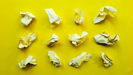 Ball crumpled paper ball isolated on a yellow background. Crumpled paper for texture. Crumpled paper after a brainstorming was thrown into the bin. A piece of yellow crumpled paper on a yellow background.の写真素材