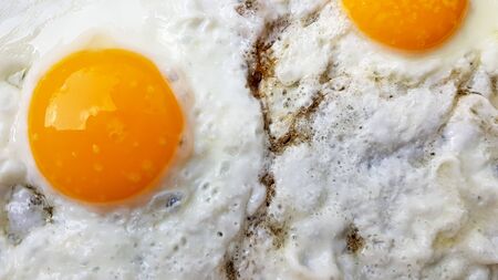 Close-up photo of two scrambled eggs in black frying pan.の写真素材