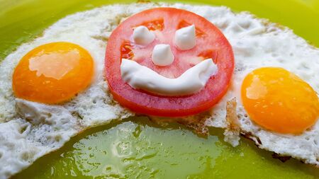 fried eggs with vegetables on a green plate, served to children.の写真素材