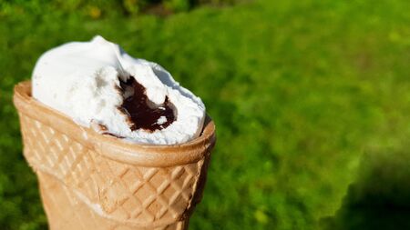 bitten ice cream in a waffle cup with chocolate filling. Bitten white ice cream with caramel on a...