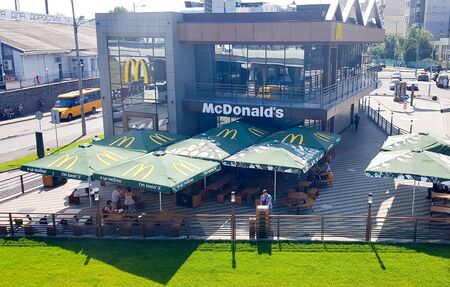 Ukraine, Kiev April 16, 2019: McDonald's restaurant in Kiev, Ukraine. McDonald's is an American chain of fast food restaurants and hamburgers. Top view from the bridge to the restaurant building with a summer terrace and parking.のeditorial素材
