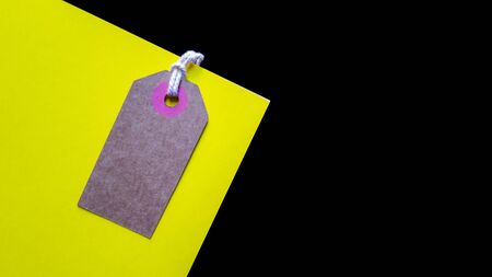 Blank brown cardboard price tag or label on yellow background. top view.の写真素材